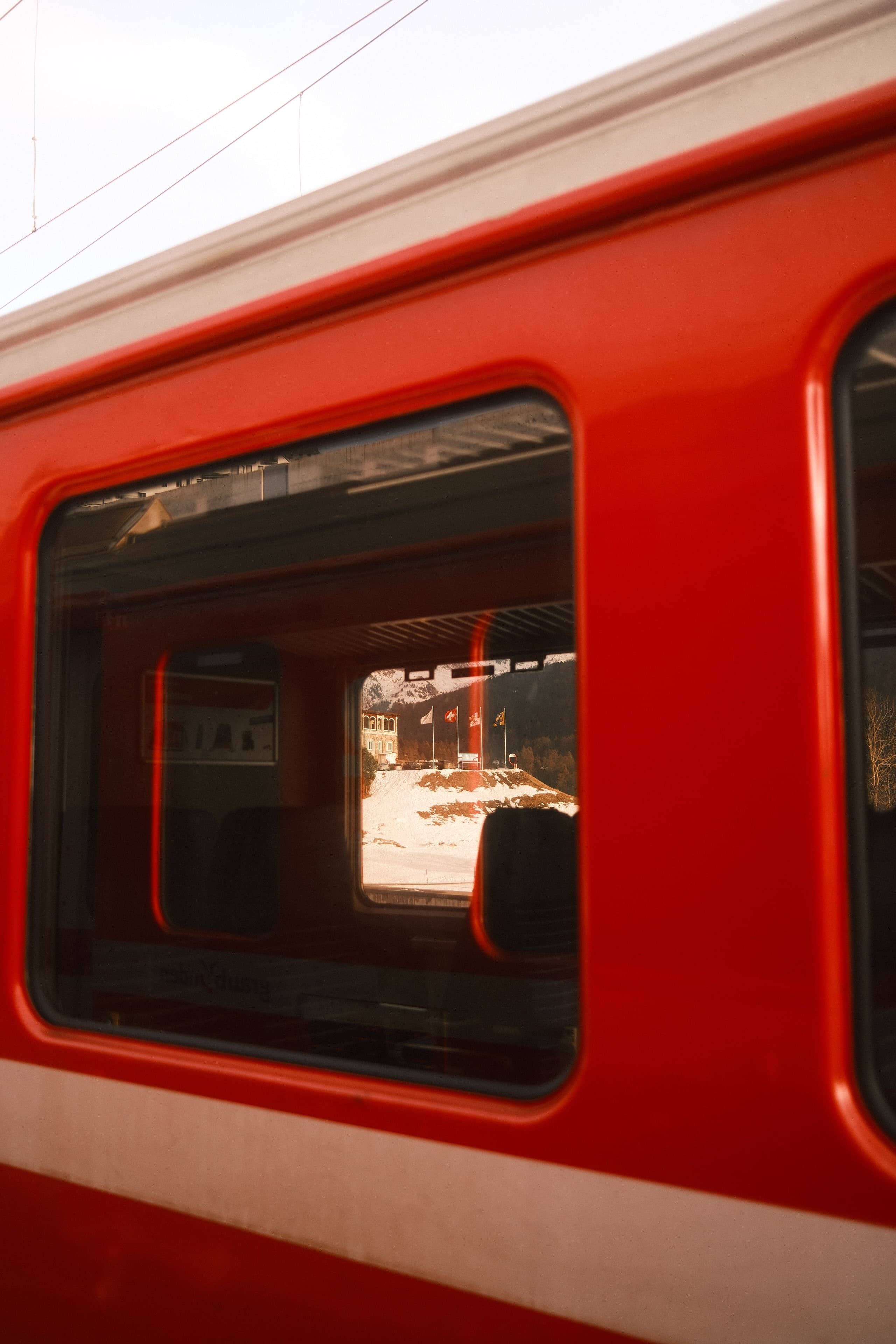 Red train door framing a winter platform through layered windows